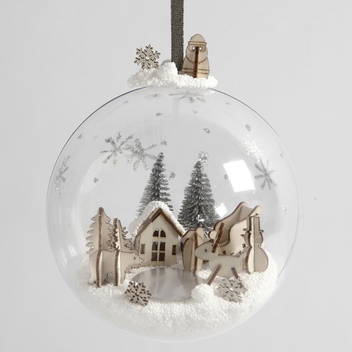 Un monde miniature en pâte à modeler foam et figurines en bois à l’intérieur d’une boule de Noël