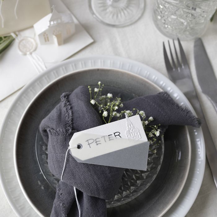 Des marque-places dans des tons blanc cassé avec une église perforée et du papier vélin