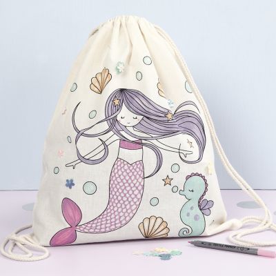 Un sac à cordon avec un motif de sirène préimprimé décoré avec des marqueurs textiles et des sequins.