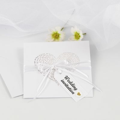 Une invitation de mariage ornée d’un ruban en satin et d’étiquettes en papier kraft