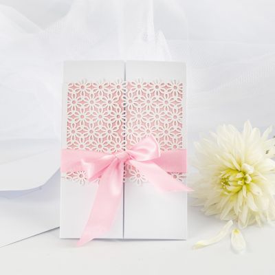 Une invitation de mariage décorée avec du carton à motif dentelle et un ruban en satin