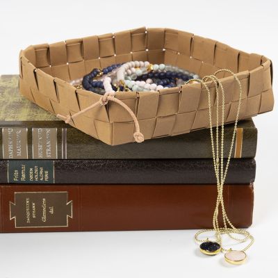 Un panier tissé à partir de bandes de papier simili cuir et fixé avec un cordon en cuir