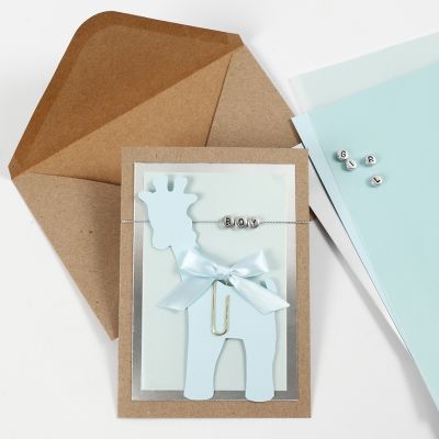 Une invitation pour un baptême avec une carte girafe et des perles lettres.