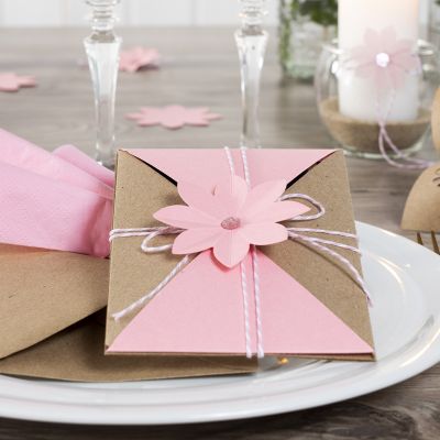 Une invitation emballée et maintenue avec du cordon de coton et une fleur découpée à l’emporte-pièce.