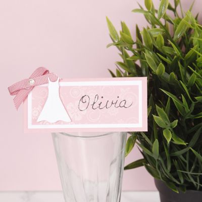 Un marque-place pour une fête de confirmation décoré avec une robe et un nœud