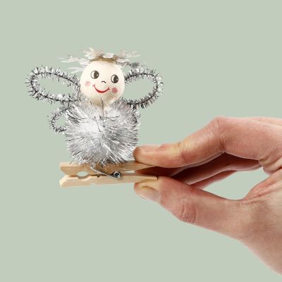 Un ange réalisé avec un pompon et des cure-pipes sur une pince à linge en bois.