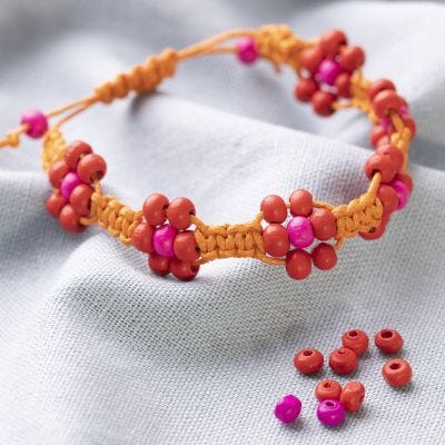 Un bracelet tressé fait avec un cordon en coton avec des perles comme de grosses fleurs