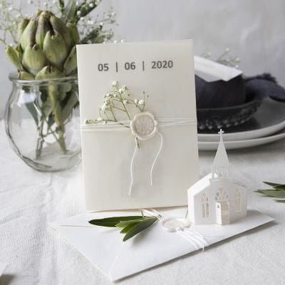 Une invitation dans des tons blanc cassé avec une église perforée et du papier vélin