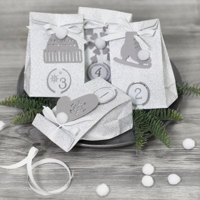 Réalisez un calendrier de l'Avent en emballant les cadeaux avec du papier décoratif et en les ornant de pompons et d'autres décorations en papier pour une présentation festive et créative