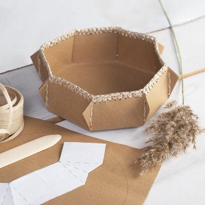 Un panier en papier simili cuir avec un bord crocheté en fil de raphia en papier