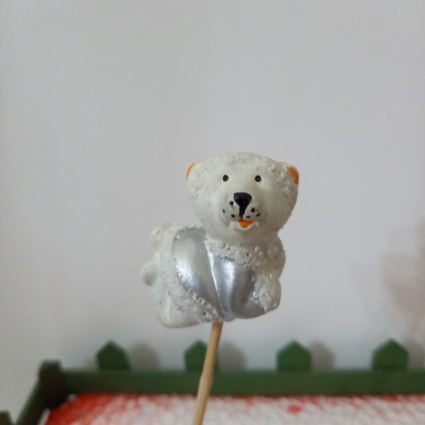 Un ours blanc couché  sur son pique  en bois - Photo n°1
